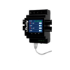 A black Shelly smart relay device is mounted on a wall, featuring a small screen displaying power usage readings and status indicators. A white cable is plugged into the bottom of the device.