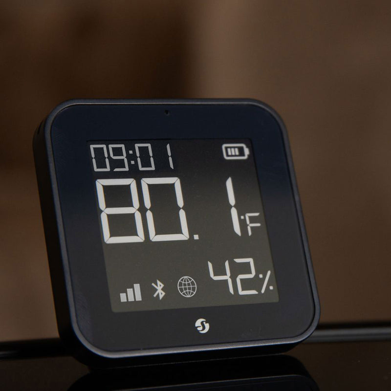 The Shelly BLU H&T Display ZB Black by Shelly USA shows the time (09:01), temperature (80.1°F), and humidity (42%) on its digital screen, with connectivity and battery icons displayed at the bottom.