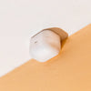 A white Apple AirPods charging case is mounted to the intersection of a white ceiling and a beige wall, resembling a security device.