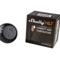 A Shelly H&T Black, a WiFi-operated humidity and temperature monitor from Shelly USA, is shown with its black box packaging featuring circuit graphics and the product website—all displayed on a white background.