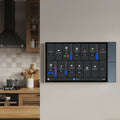 The Shelly Wall Display XL by Shelly USA is mounted on a beige wall in a modern kitchen, showing controls and stats for lights, temperature, and appliances. Wooden utensils and cookware are on the kitchen counter.