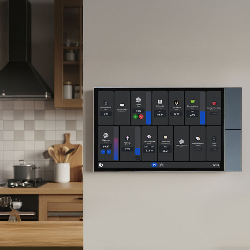 The Shelly Wall Display XL by Shelly USA is mounted on a beige wall in a modern kitchen, showing controls and stats for lights, temperature, and appliances. Wooden utensils and cookware are on the kitchen counter.