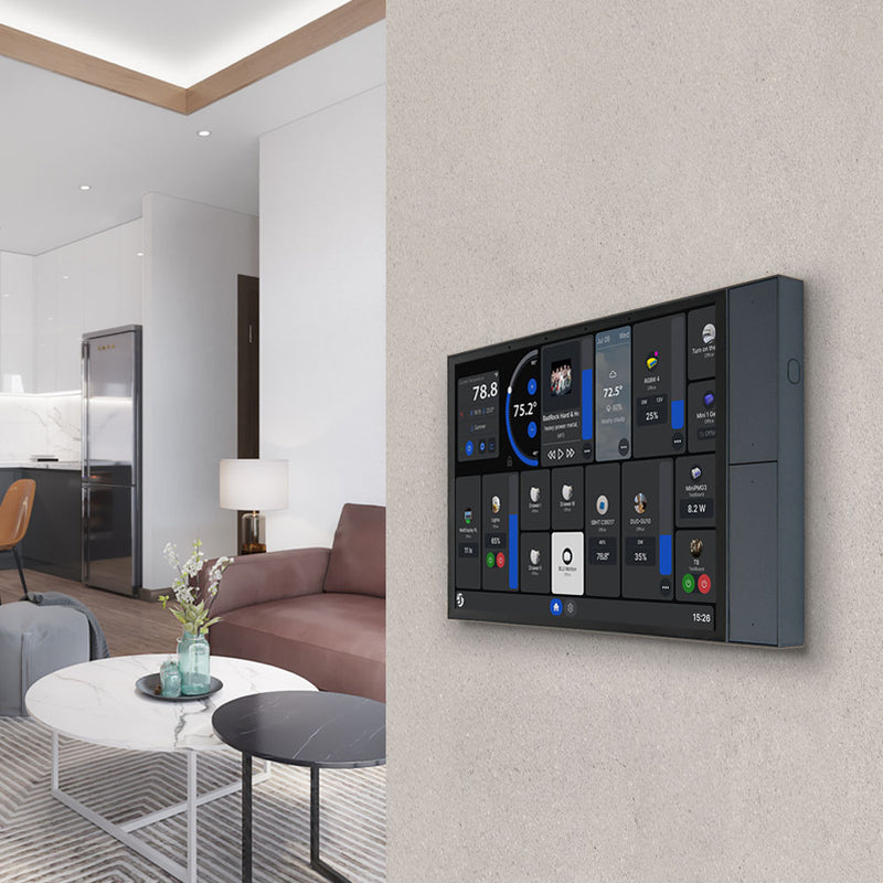 The Shelly Wall Display XL by Shelly USA is mounted on the wall, showing multiple controls. Behind it, a stylish living room with a sofa, coffee table, and an open kitchen featuring a refrigerator and lamp is visible.