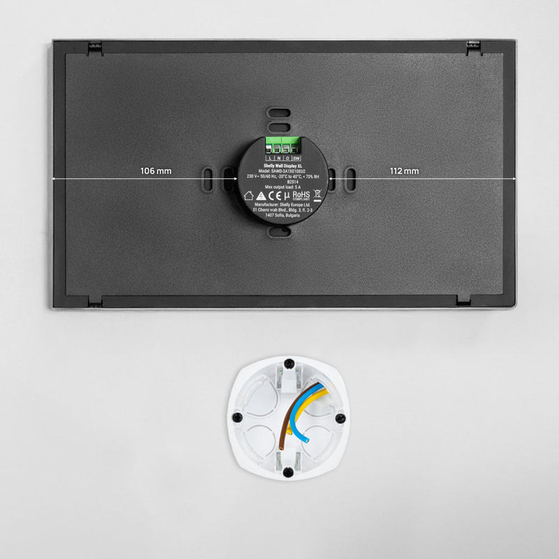 The Shelly USA Shelly Wall Display XL list is a rectangular black wall-mounted device with labels, a central round element, and measurements of 106 mm by 112 mm, shown above a white circular base with visible colored wires.