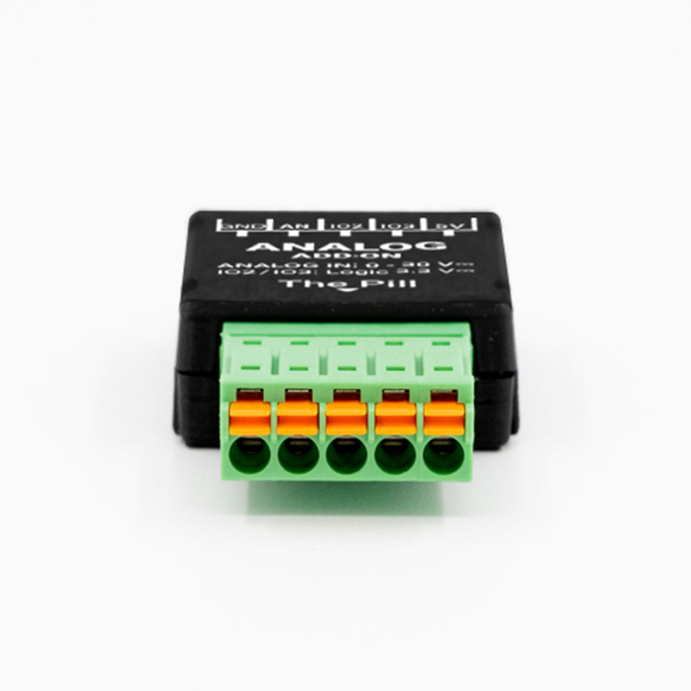 A compact black and green Shelly USA Analog 0–30V Add-on (Shelly Pill) electronic module with six orange and green terminal connectors for analog signal input or output.