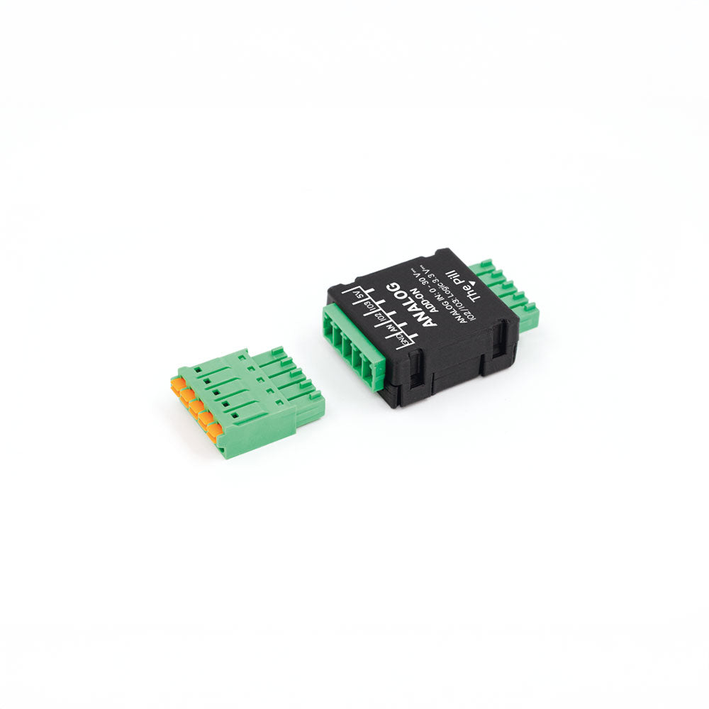 The Shelly USA Analog 0 - 30V Add-on (Shelly Pill) is a black electronic module with green terminal blocks and a separate green connector with orange pins, both shown on a white background.